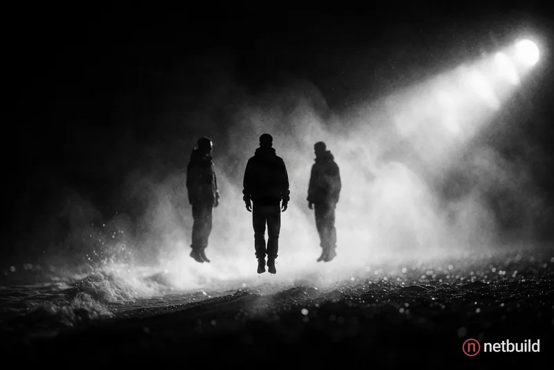 Cinematic wide shot of three levitating figures as dark silhouettes above a darkened shoreline shrouded in heavy, glowing sea mist. Deep monochromatic...