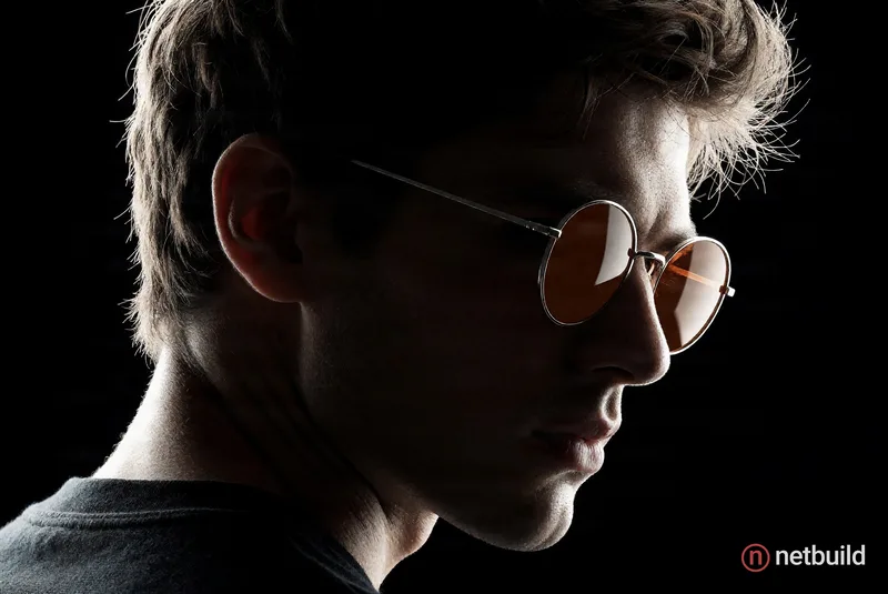 Ultra-realistic cinematic dark poster featuring a dramatic over-the-shoulder pose of a young man in a 90-45 degree side profile facing right. Deep bla...