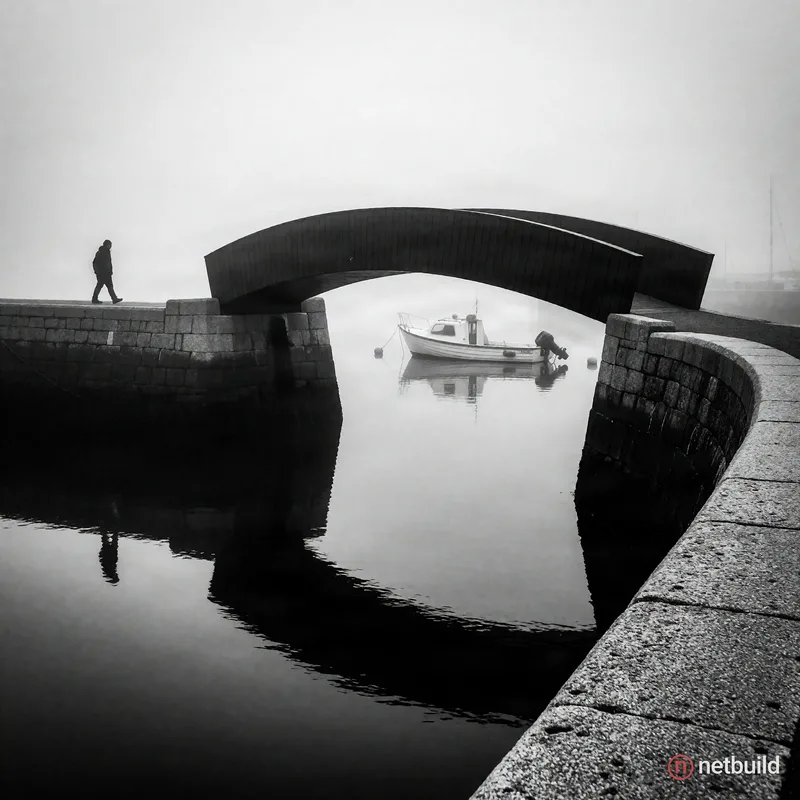 black and white photography, lone silhouetted figure walking on a curved stone pier approaching a dark modern footbridge, dense atmospheric fog, small...